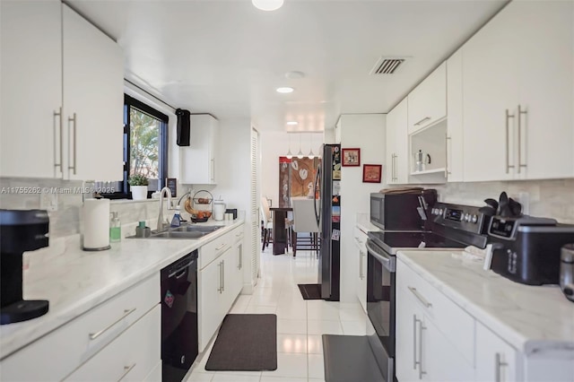 kitchen with light tile patterned flooring, a sink, visible vents, light countertops, and black appliances