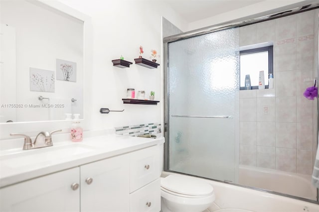 full bathroom with bath / shower combo with glass door, vanity, and toilet