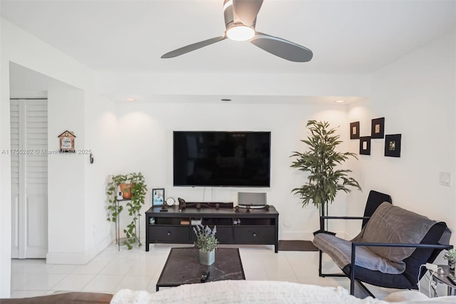 tiled living room with ceiling fan and baseboards