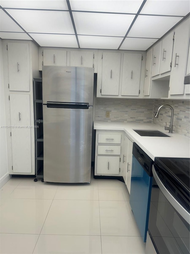 kitchen with tasteful backsplash, dishwasher, freestanding refrigerator, a sink, and light tile patterned flooring