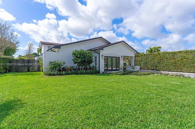 view of front of property with fence, a front lawn, and stucco siding