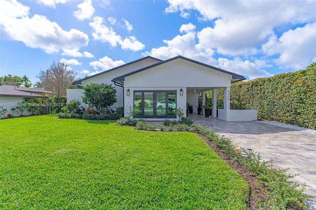 back of property with stucco siding, fence, decorative driveway, and a yard