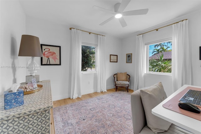 home office with light wood-style floors, baseboards, and a ceiling fan