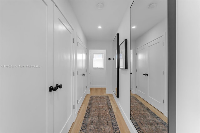 corridor with light wood-type flooring, baseboards, and recessed lighting