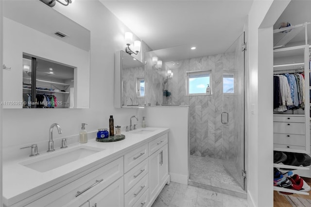 full bath featuring a stall shower, a spacious closet, visible vents, and a sink