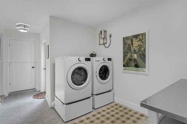 clothes washing area with baseboards and washer and clothes dryer