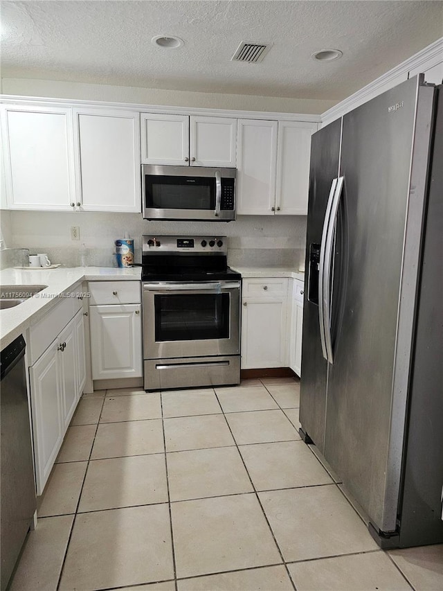 kitchen featuring stainless steel appliances, visible vents, white cabinetry, and light tile patterned flooring