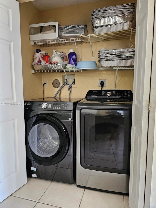laundry area with laundry area, washer and clothes dryer, and tile patterned floors