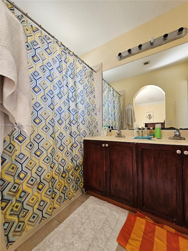 full bath featuring double vanity, visible vents, tile patterned floors, a textured ceiling, and a sink