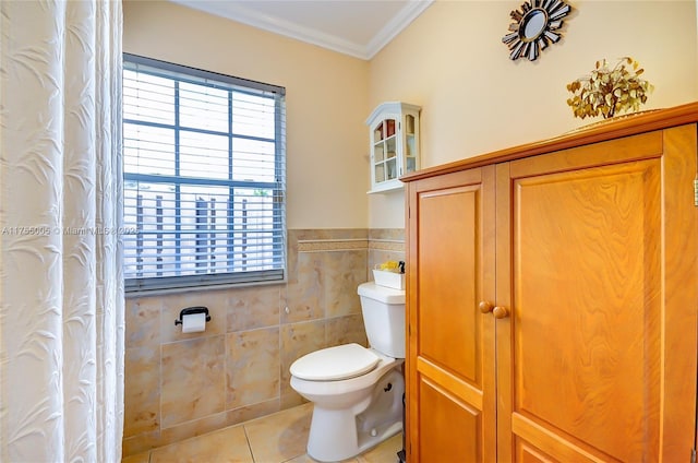 full bath with wainscoting, toilet, ornamental molding, tile patterned floors, and tile walls