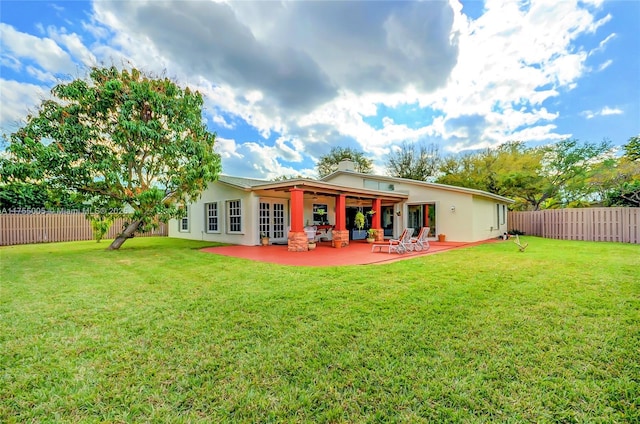 back of property with a fenced backyard, a lawn, and a patio