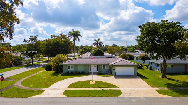 single story home with decorative driveway, central AC, a garage, a tiled roof, and a front lawn