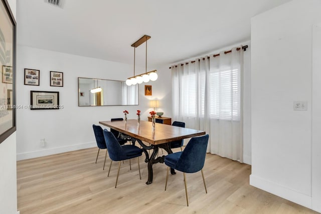 dining space featuring light wood-style flooring, visible vents, and baseboards