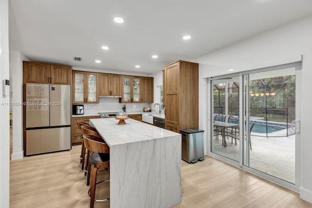 kitchen featuring visible vents, light wood-style floors, freestanding refrigerator, and brown cabinets