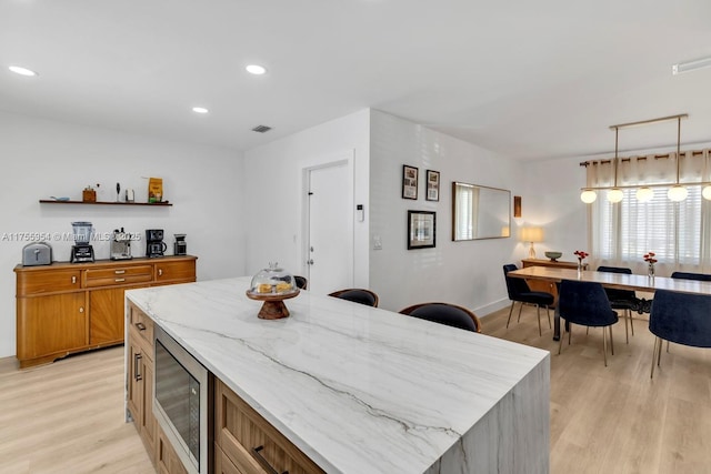 kitchen featuring open shelves, stainless steel microwave, light wood-style flooring, and brown cabinets