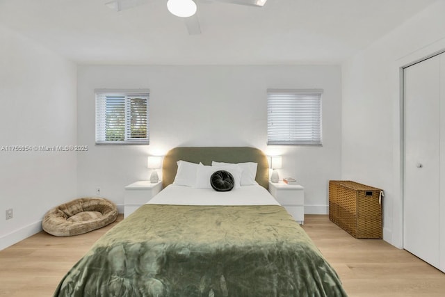 bedroom with light wood-type flooring, ceiling fan, baseboards, and a closet