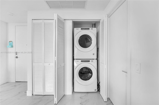 laundry area featuring visible vents, marble finish floor, laundry area, and stacked washer and clothes dryer