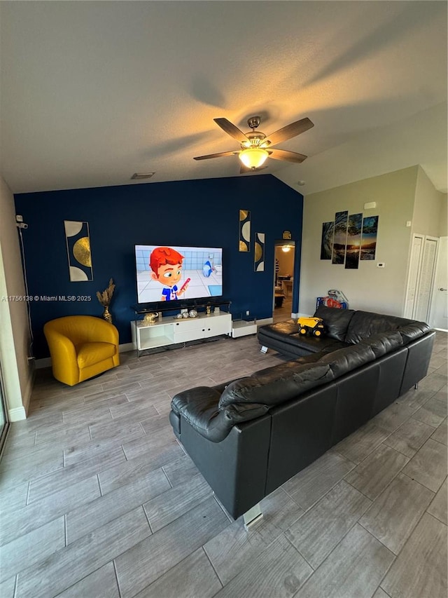 living area with wood tiled floor, visible vents, ceiling fan, and lofted ceiling