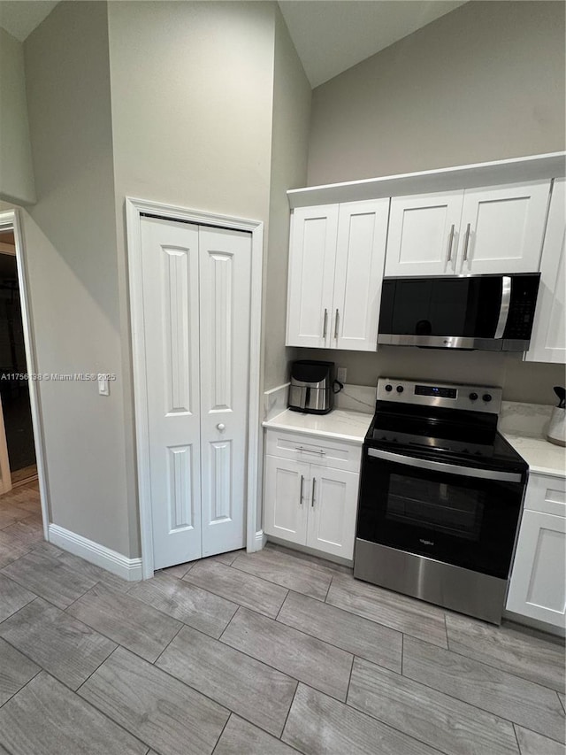 kitchen with white cabinets, baseboards, stainless steel appliances, and light countertops