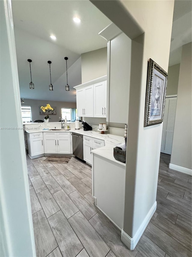 kitchen with light countertops, wood tiled floor, white cabinetry, a sink, and dishwasher