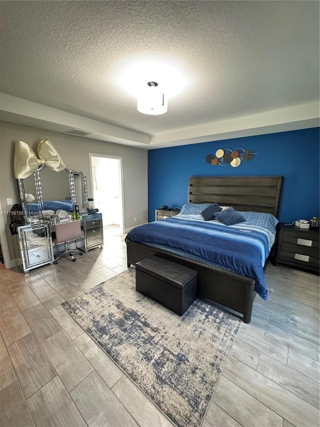 bedroom with a textured ceiling, wood finish floors, and visible vents