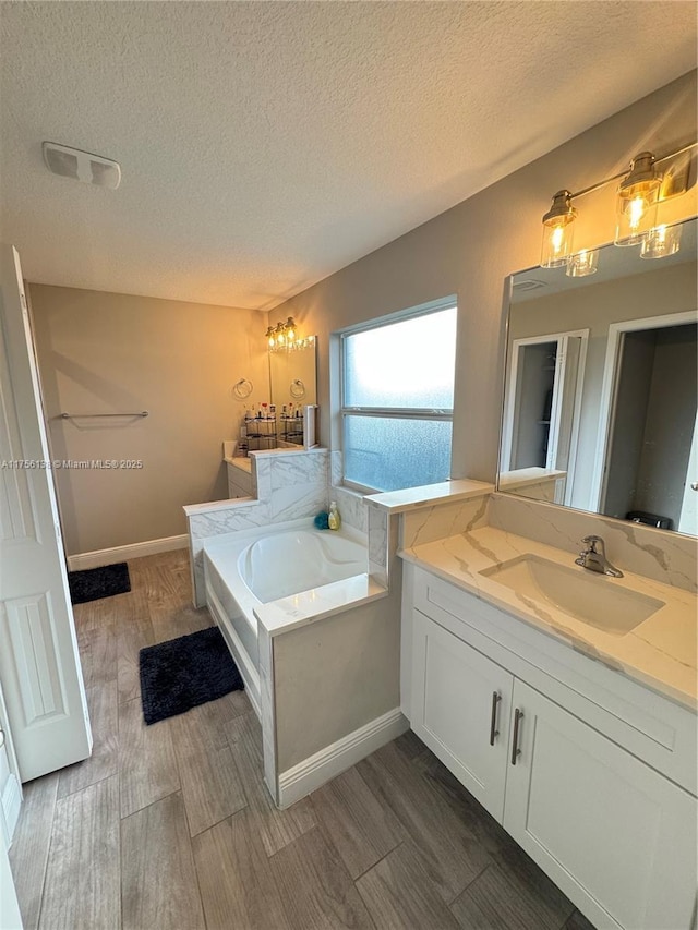 full bath with a textured ceiling, wood finished floors, visible vents, vanity, and a bath