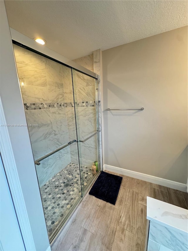 full bath featuring a shower stall, baseboards, a textured ceiling, and recessed lighting