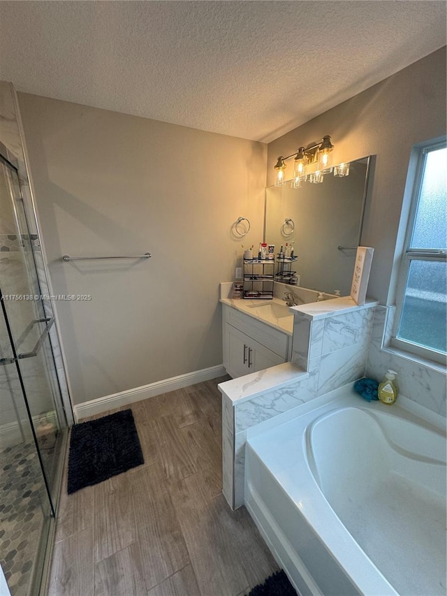 full bathroom with a garden tub, a stall shower, vanity, a textured ceiling, and baseboards