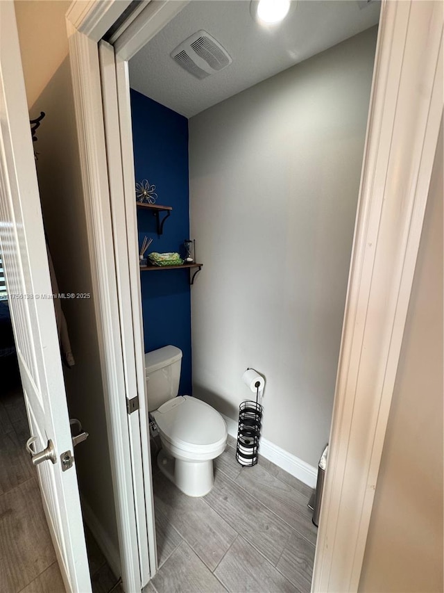 bathroom with baseboards, visible vents, and toilet