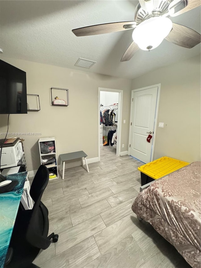 bedroom featuring a closet, a spacious closet, a ceiling fan, wood tiled floor, and a textured ceiling