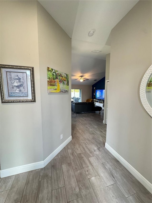 corridor with lofted ceiling, wood tiled floor, and baseboards