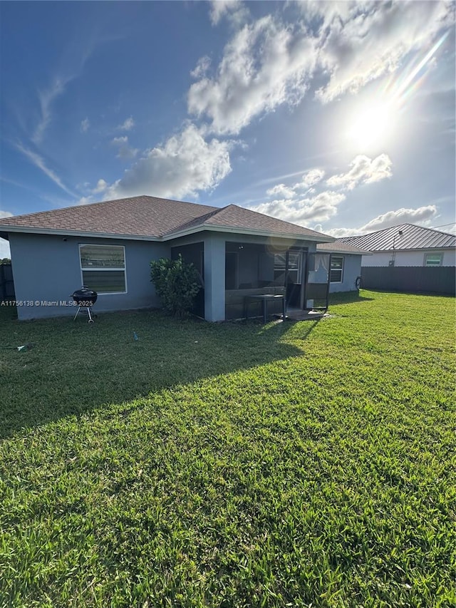 back of property with a lawn, fence, a sunroom, and stucco siding