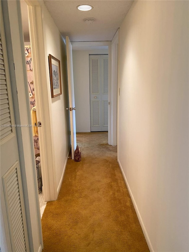 hallway featuring light carpet, visible vents, and baseboards