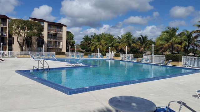 community pool with a patio area and fence