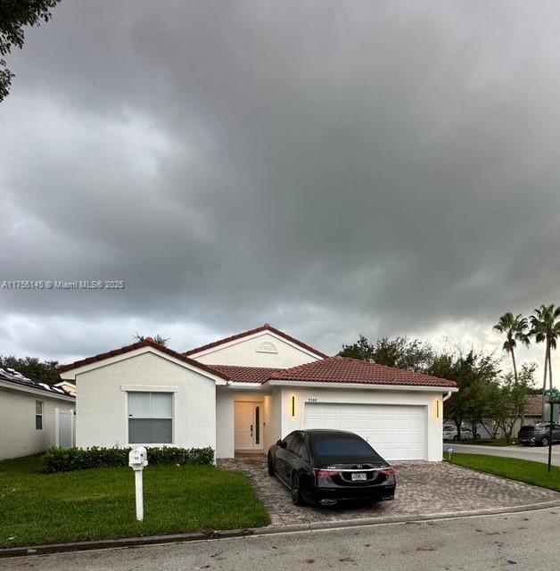 view of front facade with an attached garage, a front lawn, decorative driveway, and stucco siding