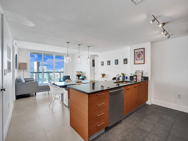 kitchen featuring dark countertops, brown cabinets, open floor plan, stainless steel dishwasher, and a sink