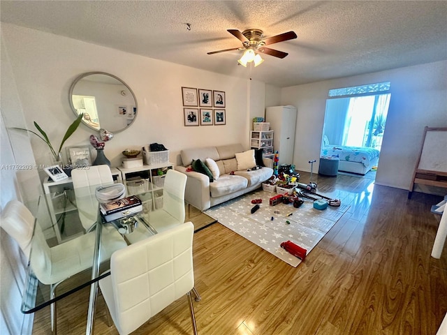 living room featuring ceiling fan, a textured ceiling, and wood finished floors