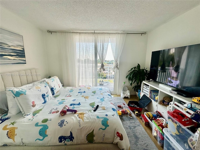 bedroom with access to exterior, a textured ceiling, and wood finished floors