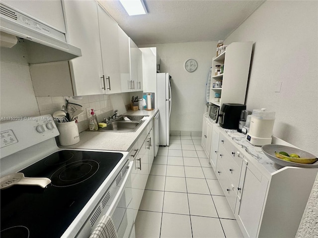 kitchen with under cabinet range hood, white appliances, a sink, light countertops, and backsplash