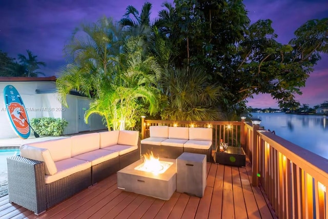 wooden deck with a water view and an outdoor living space with a fire pit