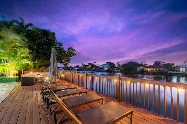 deck at dusk featuring a water view