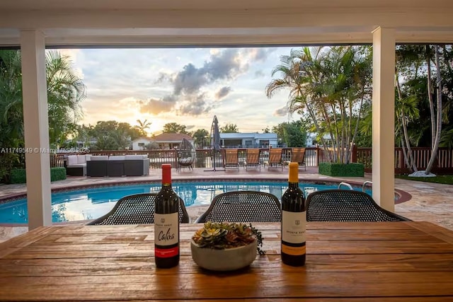 pool at dusk with fence, an outdoor living space, a fenced in pool, outdoor dining space, and a patio area