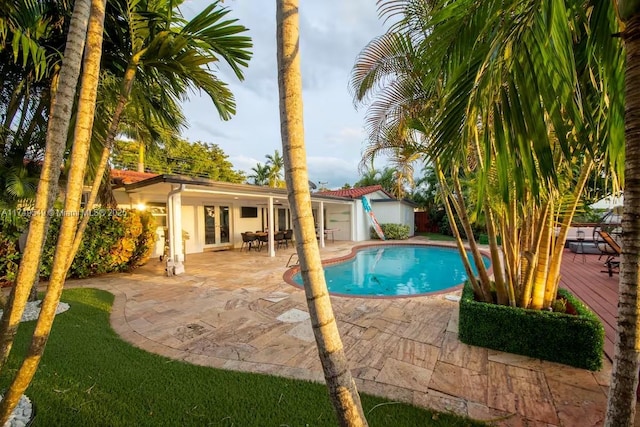 view of pool featuring a fenced in pool, french doors, a patio area, and a wooden deck