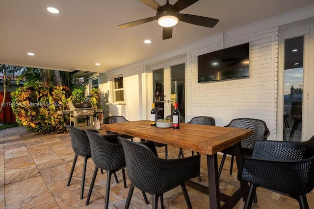 dining room with brick wall, stone tile floors, a ceiling fan, and recessed lighting