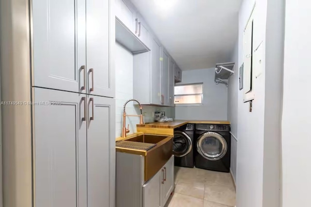 laundry room featuring light tile patterned floors, separate washer and dryer, a sink, and cabinet space