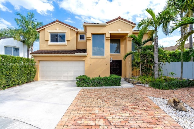 mediterranean / spanish-style house with a garage, a tiled roof, fence, decorative driveway, and stucco siding