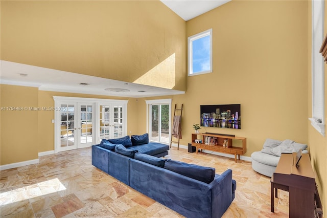 living room with visible vents, baseboards, a towering ceiling, ornamental molding, and french doors