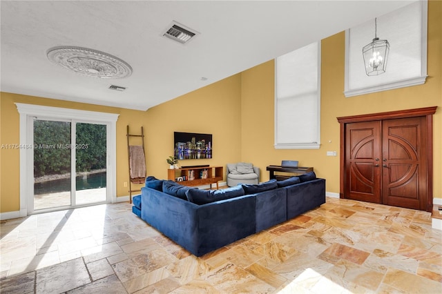 living area with baseboards, visible vents, and stone tile flooring