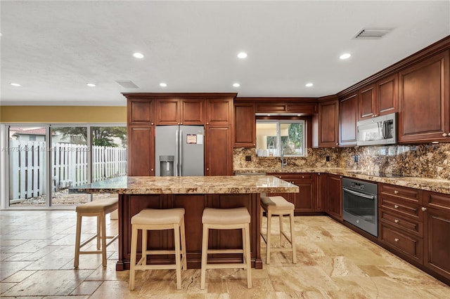 kitchen featuring appliances with stainless steel finishes, stone tile flooring, visible vents, and tasteful backsplash