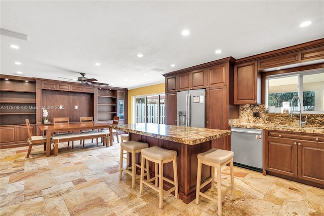 kitchen with a center island, stainless steel appliances, decorative backsplash, a sink, and a kitchen breakfast bar